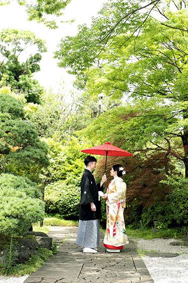 源心庵の庭で相合傘で見つめ合う新郎新婦