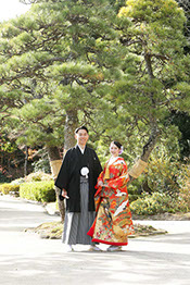 肥後細川庭園にかかる橋の上で和傘を持ちポーズをとる新郎新婦