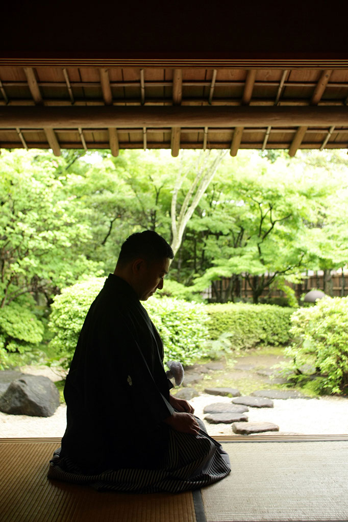 夏もみじを背景にあぐらで座る新郎